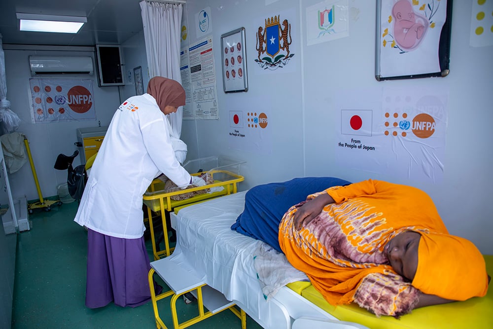 Midwife Farhiya Adan Ahmed checks Iqra's newborn at the MMC in Daynile. ©UNFPA/Usame Nur